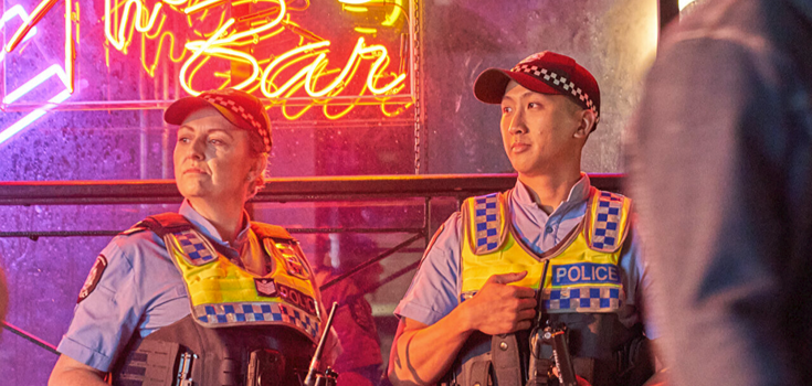 Two police officers standing infront of sign